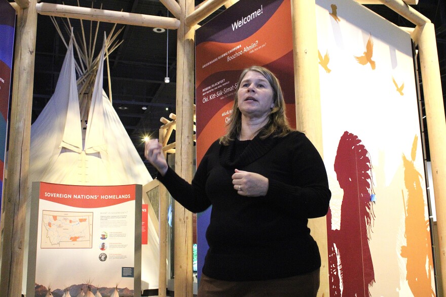 Molly Kruckenberg, executive director of the Montana Historical Society, speaks during a tour of the Montana Heritage Center. She stands in front of exhibits featuring a tipi, a welcome sign with Native greetings, and a panel titled “Sovereign Nations’ Homelands,” which includes a map and information about tribal sovereignty.