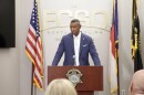 Sheriff Bobby Kimbrough behind a podium speaking at a press conference with three flags behind him. 