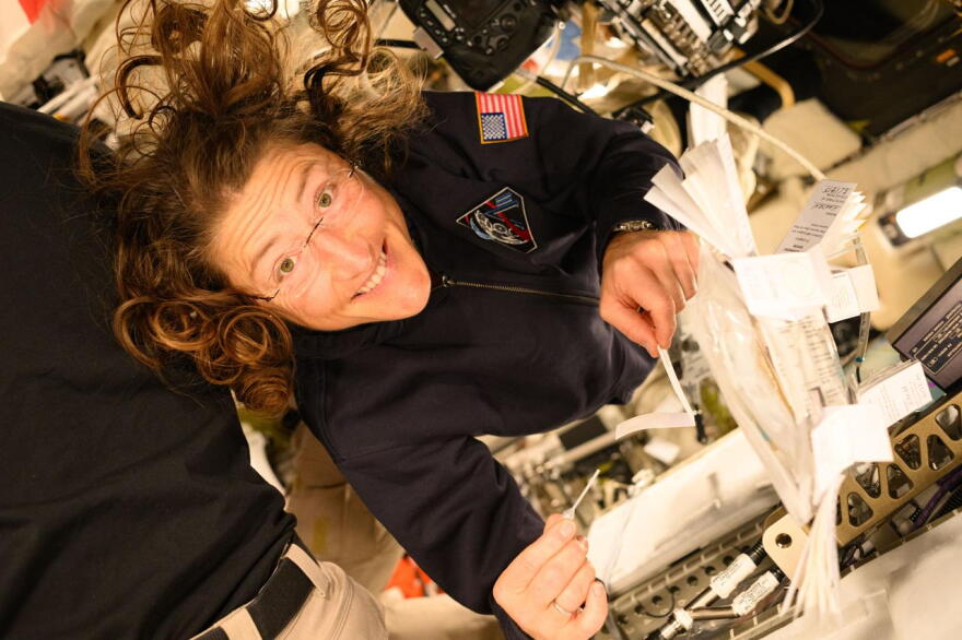 NASA astronaut Christina Koch smiles at the camera as she holds a pipette and saliva booklet for the Artemis II Immune Biomarkers study. Samples will be analyzed for proteins, enzymes, and other biomarkers that monitor immunity, inflammation, nutritional status, bone health, and radiation effects, to determine how crewmembers adapted to deep spaceflight conditions.