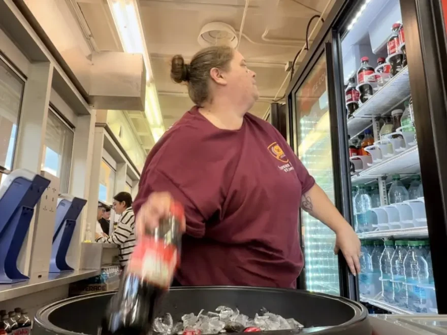 Stephanie Peterson manages the concession booth at Deer Park High School’s stadium. She grabs a soda out of the ice box.