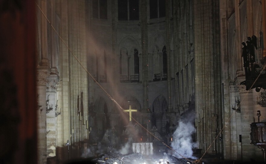 Smoke rises in front of the cross in the interior of Notre Dame Cathedral in Paris. A catastrophic fire engulfed the cathedral on Monday, as tourists and Parisians looked on from the streets below.