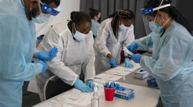 Health care workers Henry Paul, from left, Ray Akindele, Wilta Brutus and Leslie Powers process COVID-19 rapid antigen tests. (AP Photo/Jae C. Hong, File)