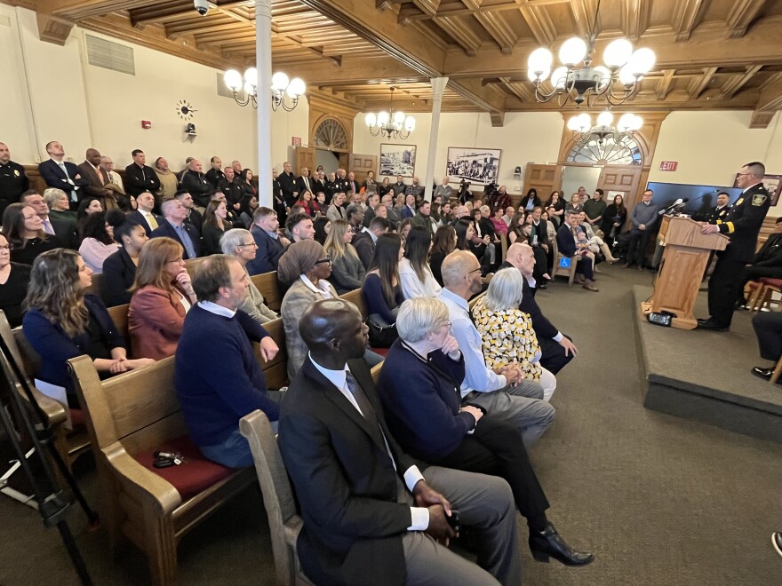 Chief Rusin addresses a standing room-only crowd inside council chambers. All councilors attended, and most can be seen in the front two rows.