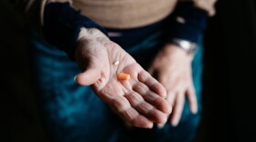 a person holds two pills, one orange and one while, in hands