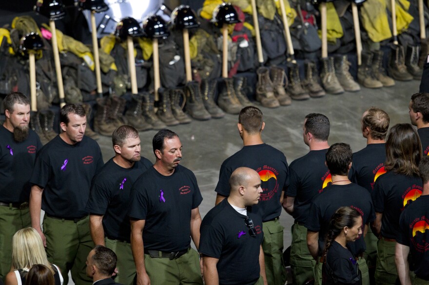 Former Granite Mountain Hotshot firefighters walk past ceremonial firefighter boots and gear during a memorial honoring 19 fallen firefighters in Prescott Valley, Ariz., on Tuesday.