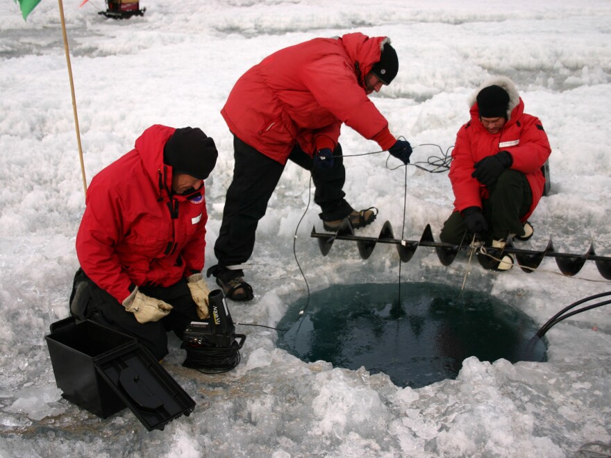 John Priscu, Phil Lee and Mike Lizotte use an underwater camera to check the progress of a hole being melted on Lake Bonney, Antarctica, in 2008.