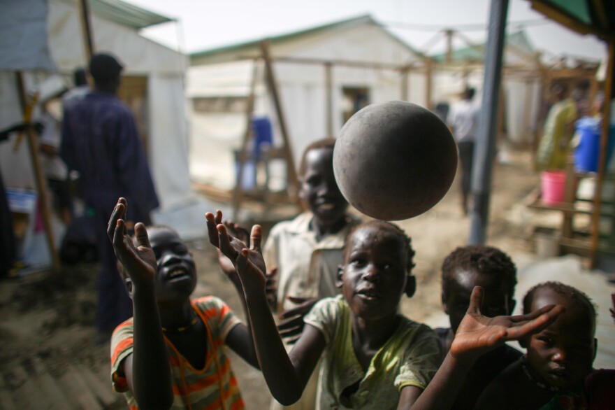 Kids who are waiting inside the hospital compound play with a balloon outside the wards.
