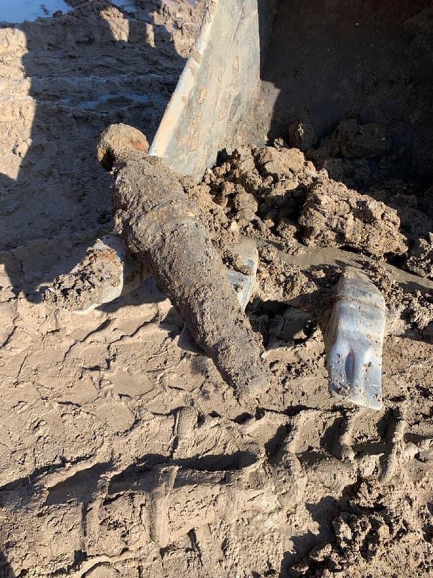 A partially uncovered metal object stuck in the mud