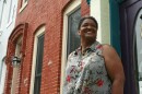 Jeanetta Churchill stands outside of her Baltimore row house. She says she has to keep her air running constantly in the summer in order to manage her bipolar disorder.