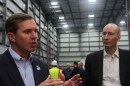Governor Andy Beshear stands in an industrial facility alongside U.S. Department of Energy Deputy Secretary David Turk.