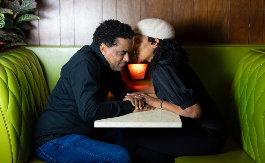 Picture of a couple whispering in a booth 