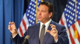 Man is suit stands at podium and speaks 