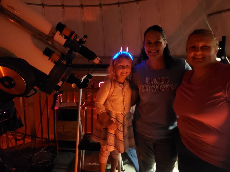 Julia Kroker came with her 6-year-old daughter Jane to see the eclipse. They pose with a friend (far right) in front of a MEADE LX200 telescope.