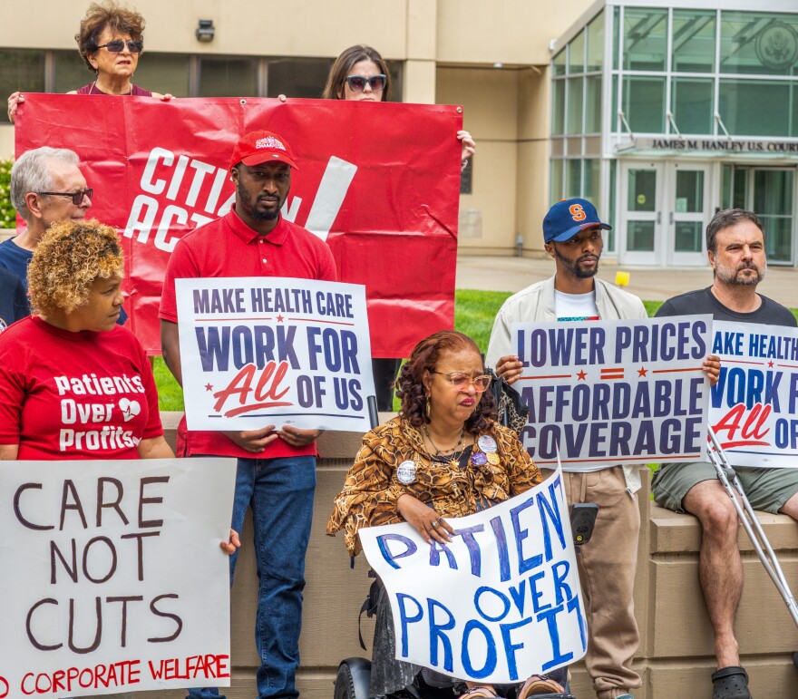 Lawmakers and advocates rally with placards in hand at the James Hanley Federal Building in Syracuse. 