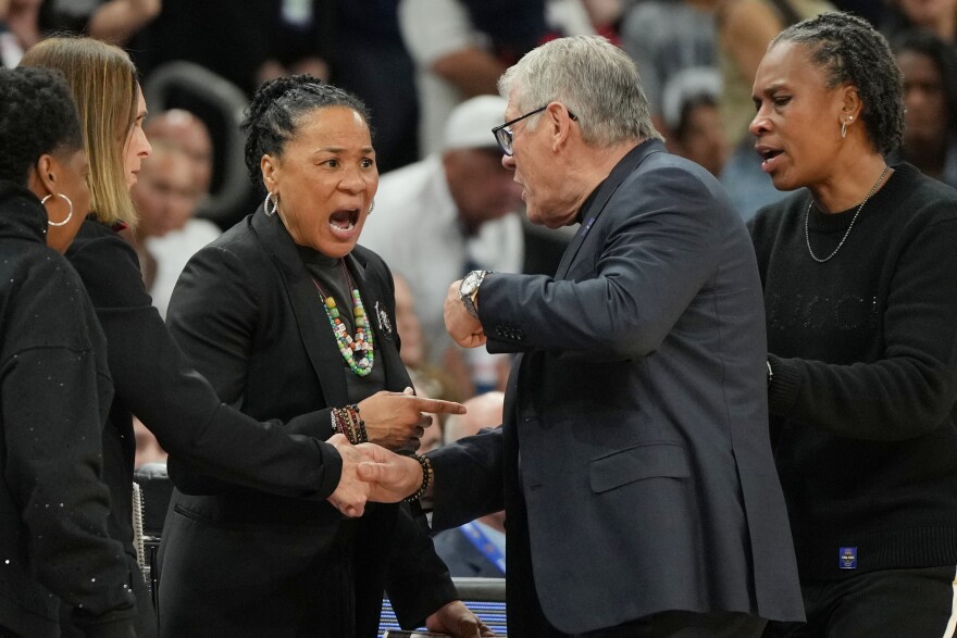 South Carolina head coach Dawn Staley and UConn head coach Geno Auriemma talk during the first half of a woman's NCAA college basketball tournament semifinal game at the Final Four, Friday, April 3, 2026, in Phoenix. (AP Photo/Rick Scuteri)