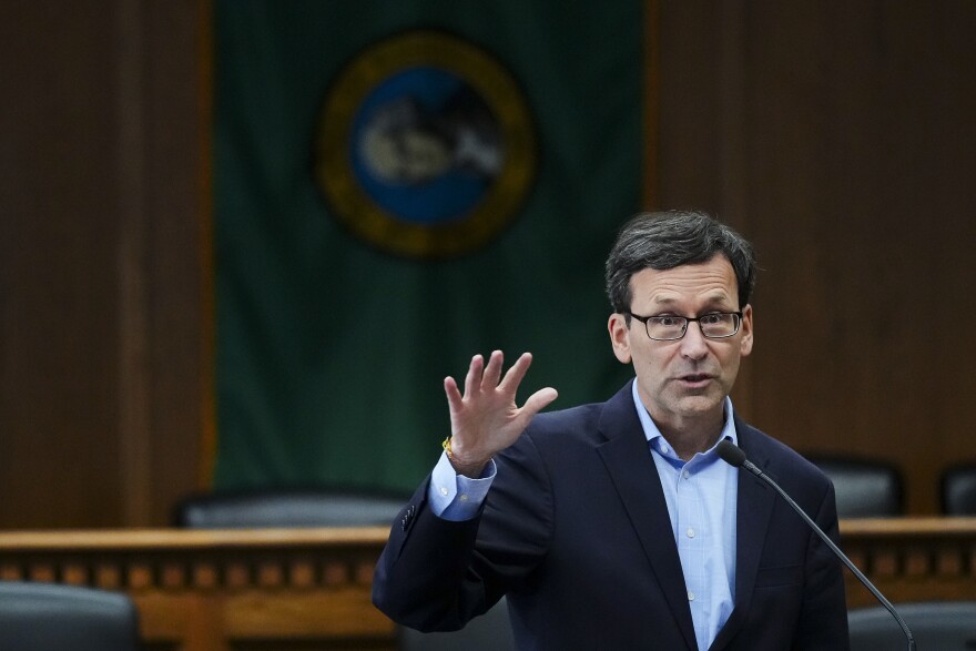 Gov. Bob Ferguson of Washington raises his hand as he talks.