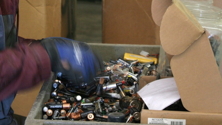 E-waste worker sorting through a box of used batteries