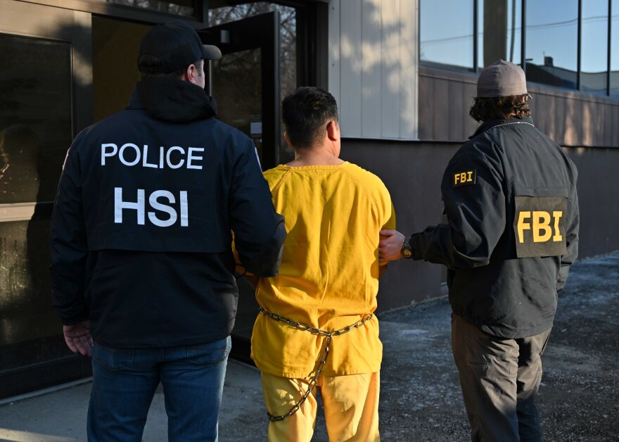 A Department of Homeland Security officer and an FBI agent flank a man in a photo of immigration enforcement operations posted by the Anchorage FBI office on Monday, Feb. 3, 2025.