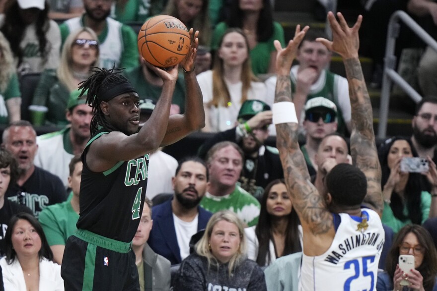 Boston Celtics guard Jrue Holiday takes a shot over Dallas Mavericks forward P.J. Washington (25) during the first half of Game 2 of the NBA Finals basketball series, Sunday, June 9, 2024, in Boston. (AP Photo/Steven Senne)