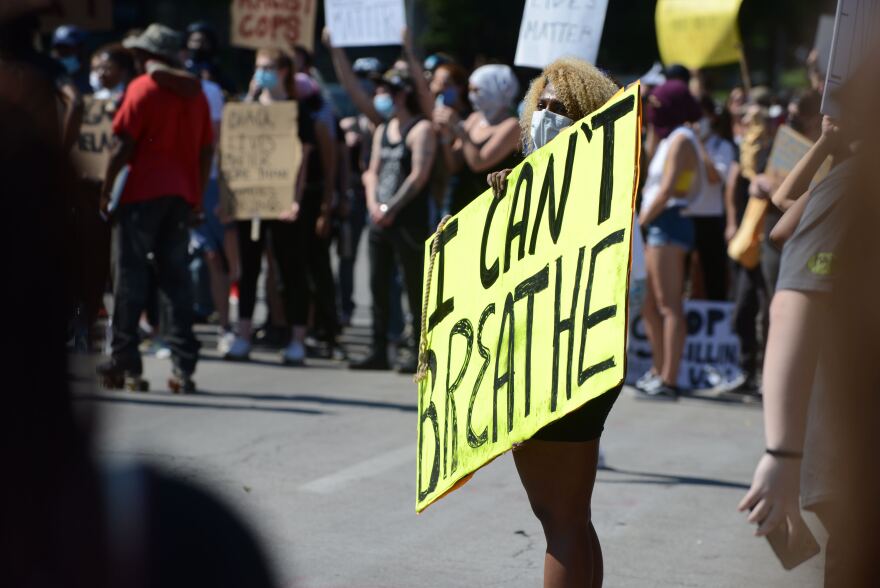 A protester walks down J.C. Nichols Parkway between police and protesters. On Sunday, activists have been allowed to rally their cohorts from the street. On Saturday, protesting from the street led to arrests.