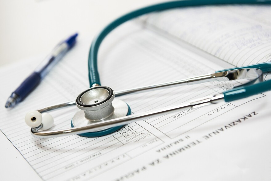 A blue stethoscope and a pen lay on a barely legible document in this stock image.