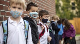 Kindergarten students at St. Peter School wait in a line outside before heading into school in the morning. (Robin Lubbock/WBUR)