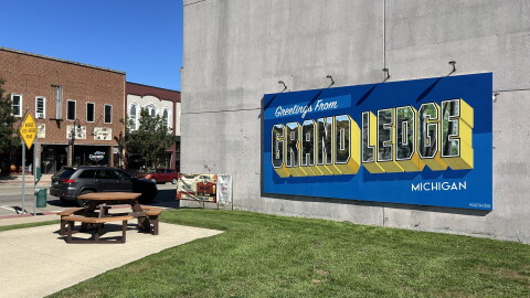 A large blue sign reads "Greetings from Grand Ledge, Michigan"