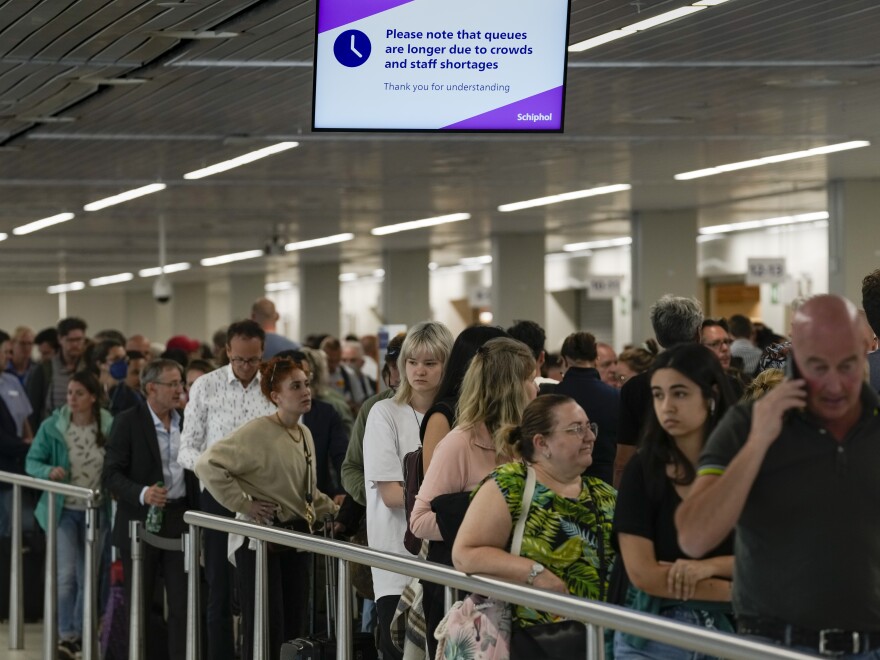 Travelers wait in long lines to check in and board flights at Amsterdam's Schiphol Airport, Netherlands, Tuesday, June 21, 2022.