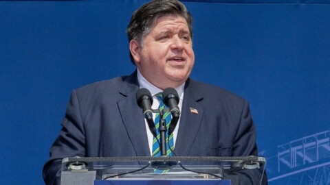 A man in a suit speaks at a podium