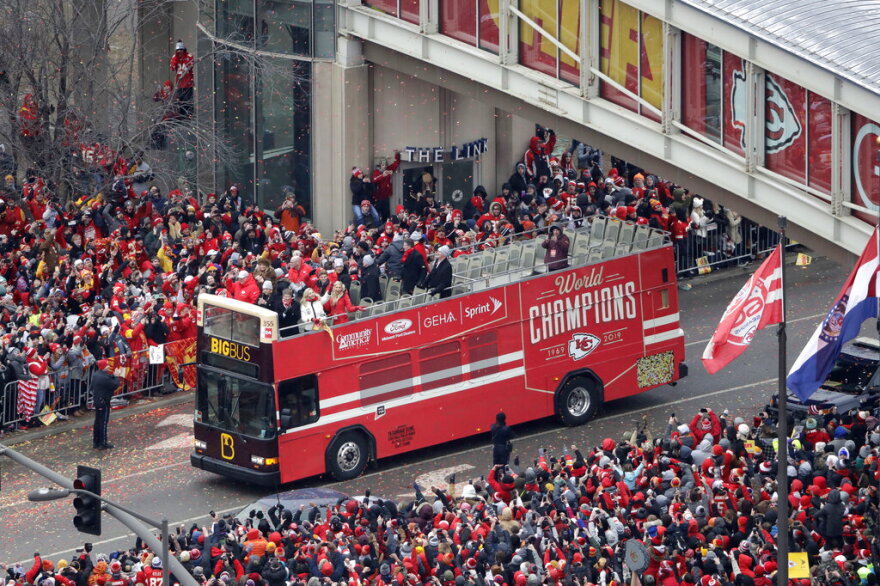 Kansas City Chiefs head coach Andy Reid, front left, and owner Clark Hunt, front right, ride on a bus during parade through downtown Kansas City, Mo., Wednesday, Feb. 5, 2020 ,to celebrate the Chiefs victory in the NFL's Super Bowl 54. (AP Photo/Charlie Riedel)