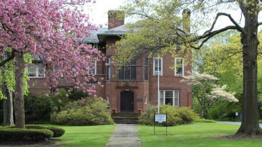 The Rochester Academy of Medicine - a historic brick building - viewed from the front with magnolias and other flower trees in bloom