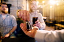 Drunk man with a beer in hand giving car key to the sober friend while enjoying in the bar.