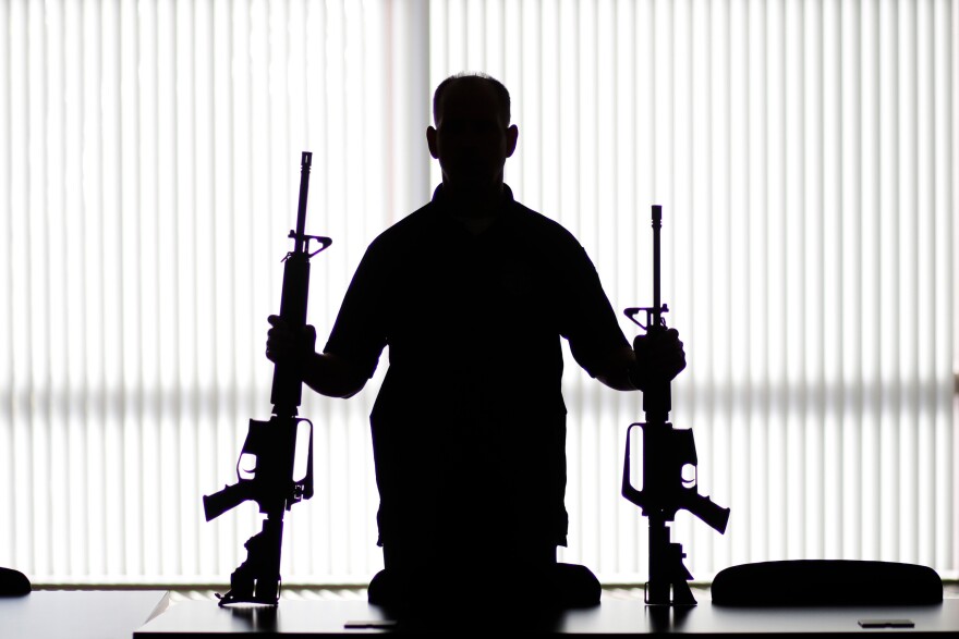 An ATF agent poses with homemade rifles, or "ghost guns," at an ATF field office in Glendale, Calif in Aug., 2017. There's a growing industry of companies that sell gun kits, instructions, and do-it-yourself components online to help people build their own guns.