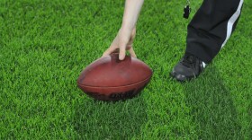  FILE: A referee sets down an American football on the ground. 