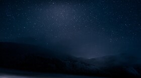 Beautiful blue dark night sky with many stars above snowy mountains