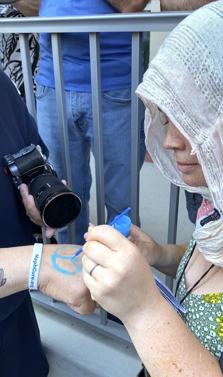 Raven White, a Christian minister in Ocala, painted peace signs on fellow protesters’ hands.