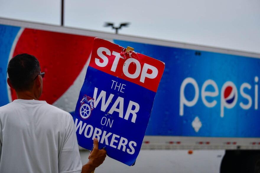 A union worker pickets outside a Pepsi bottling facility in Munster as a truck leaves the driveway.