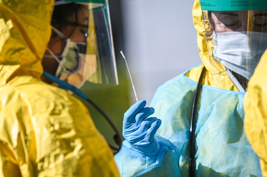 A health care worker holds a swab used for COVID-19 testing at the ProHEALTH testing site in Jericho, N.Y., March 24, 2020.