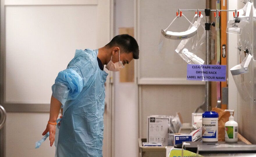 Respiratory therapist Bailey Synhavong begins to put on protective equipment, which will include a face shield, gloves, gown, head cover and mask, before going into a patient's room in the COVID intensive care unit at UW Medical Center on Tuesday.