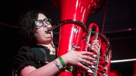 A woman in a green dress playing a red tuba