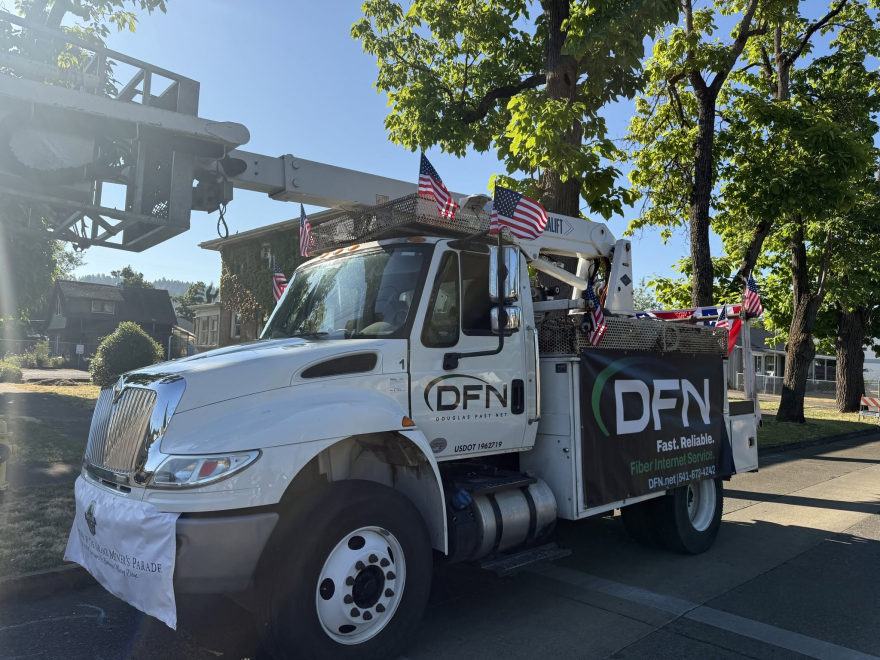 A white bucket truck is shown, with DFN advertised on the side. It is also decorated with mini American flags. 