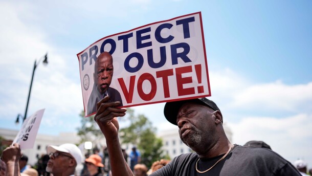 Aaron McGuire sings a spirtual song and holds a sign reading "Protect our vote" during a voting rally, Saturday, May 16, 2026, in Montgomery, Alabama.