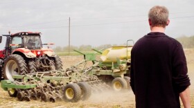 Hans Schmitz watches as the soybean planter heads down the field Thursday morning in Posey County. His farm corporation is family-owned and operated, primarily working with corn and soy. This planter is operated by Scott Dougan.