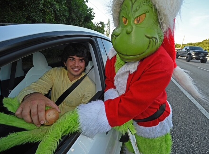 Recently retired Monroe County Sheriff’s Office Colonel Lou Caputo, right, donned a Grinch costume to stage an awareness-raising holiday traffic patrol at Key Largo School. Drivers who viuolate local traffic laws during the patrol are given a choice — ticket or onion — and a short lecture on safe driving by Caputo.