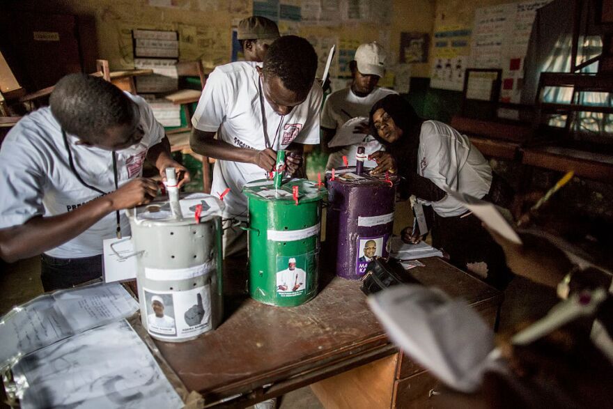 Polling officials check the seals on the voting drums Friday at a polling station in Banjul.