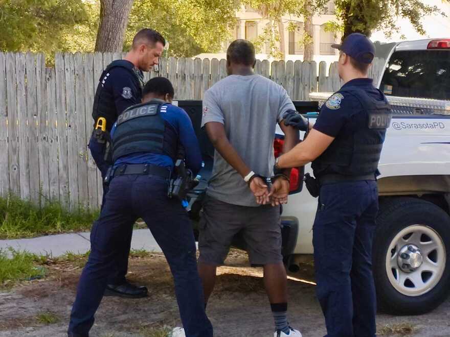 Sarasota Police Officers arrest a man on June 16 on a warrant for failure to appear. The arrest happened outside the Resurrection House, a homeless day shelter in downtown Sarasota, where officers recognized the man when he entered to seek services. Officer Nathan Lynn (left) said the officers had no choice but to arrest the man because of the warrant, but he was confident the charge would be dismissed, as the man had only failed to appear in court because he was in a drug recovery program in another county.
