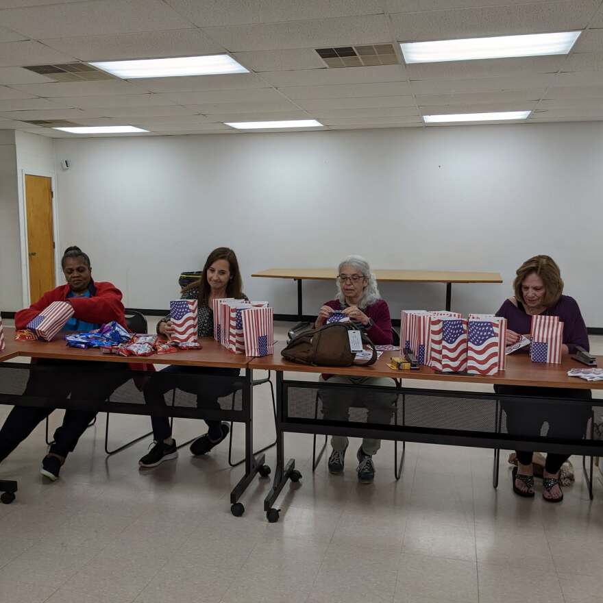 Volunteers for the Retired Senior Volunteer Program of the YWCA of McLean County seated at a table and preparing gift bags.