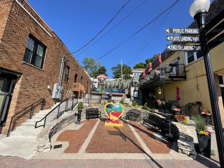 View of Parkville's Pocket Park, a small tiered park with benches, potted flowers, statues, and a KC heart sculpture in the middle.