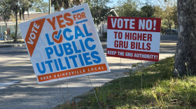 Two signs for and against removing the GRU Authority on the driveway to the North Central Florida YMCA.