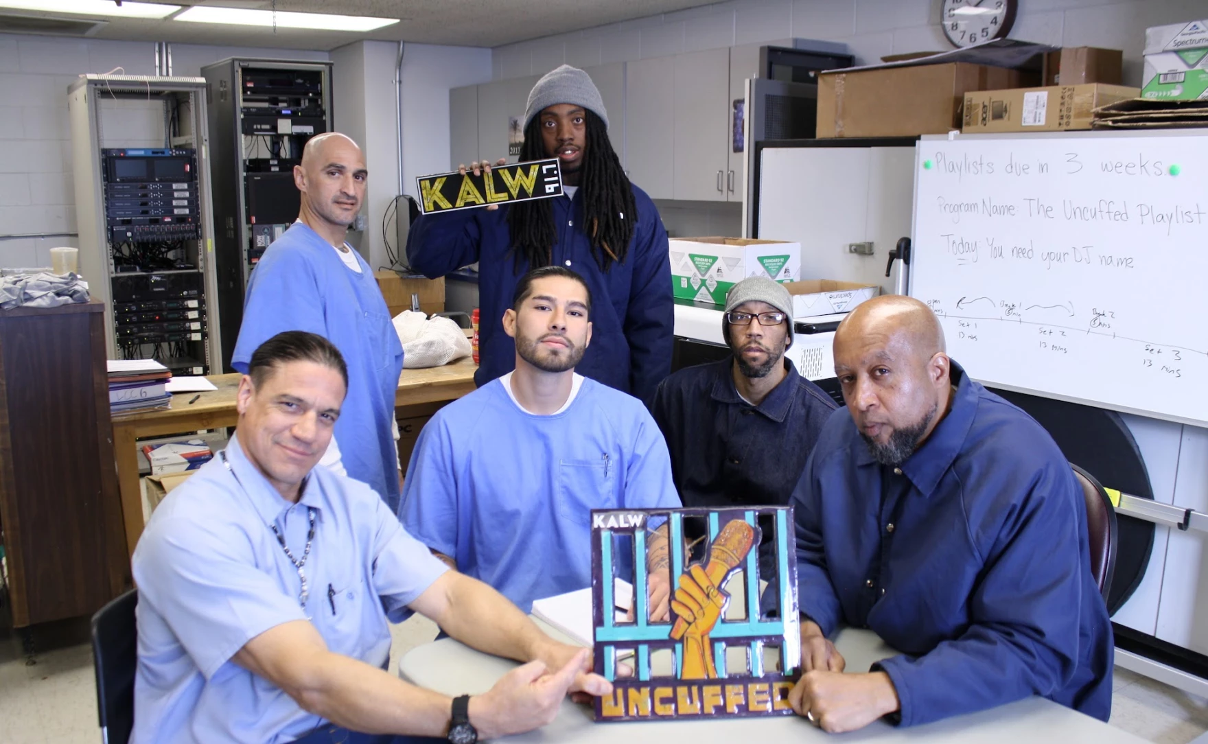 A group of incarcerated men hold a sign that says KALW UNCUFFED